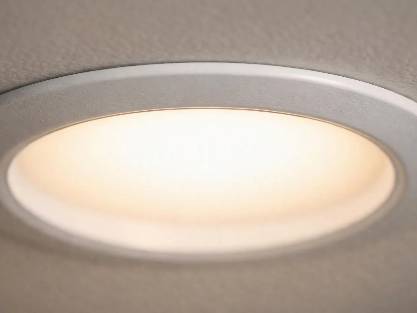A glowing recessed ceiling light sits in a textured beige ceiling